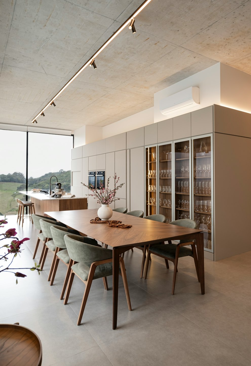 Modern open-plan kitchen and dining room with green chairs around a wooden table.