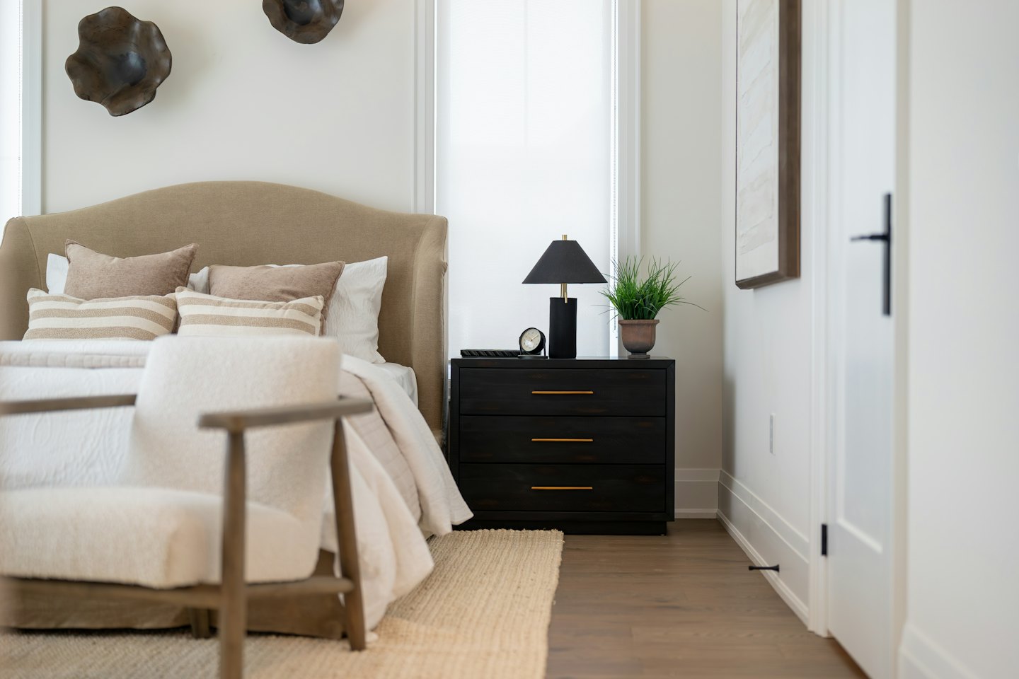 Contemporary bedroom with beige upholstered headboard and striped pillows.